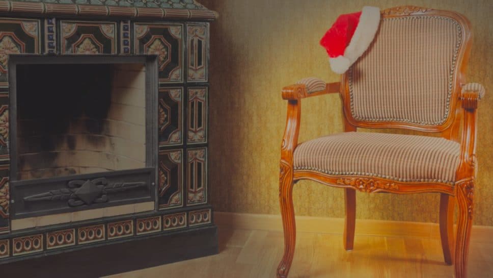 Chair with Santa hat next to fireplace.