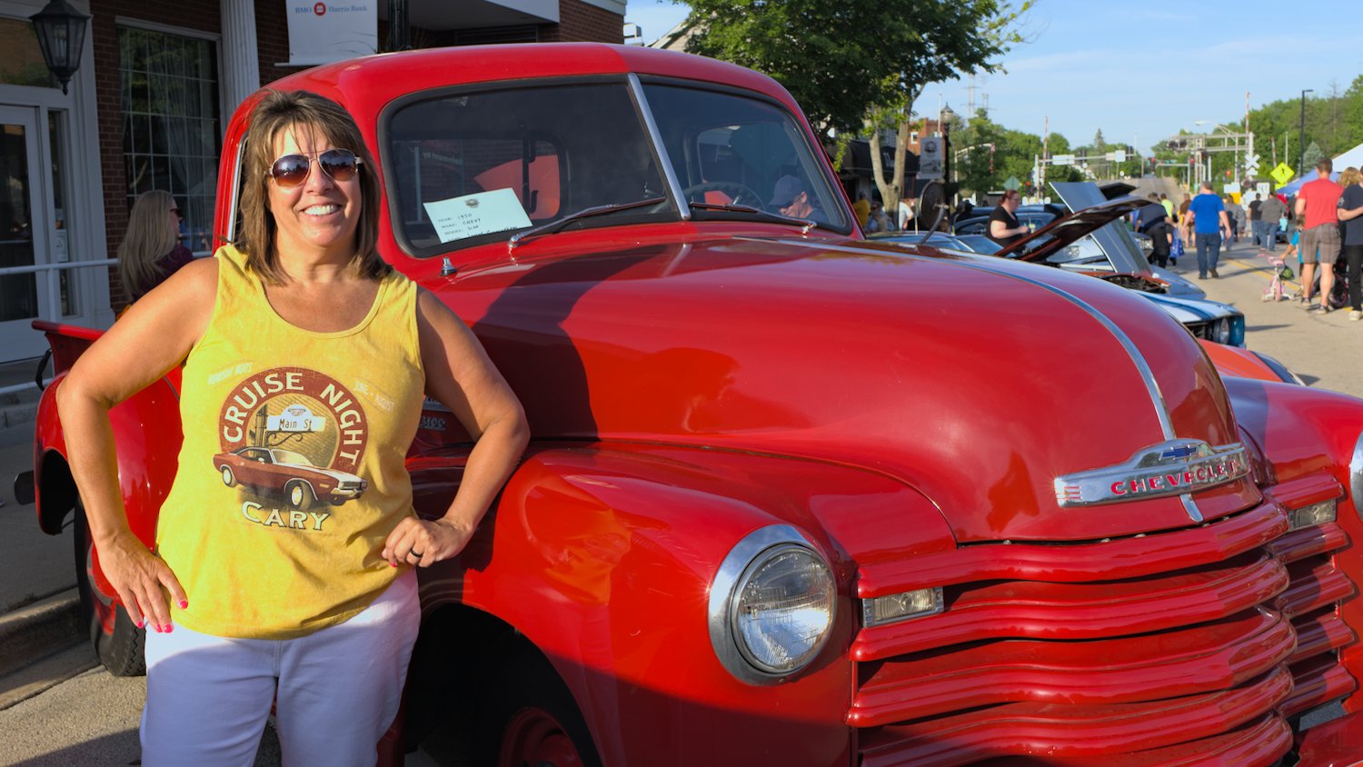 Lynn Caccavallo, President & CEO of the Cary-Grove Area Chamber of Commerce, next to an "Old Red" 1950 Chevy 3100 pickup truck.