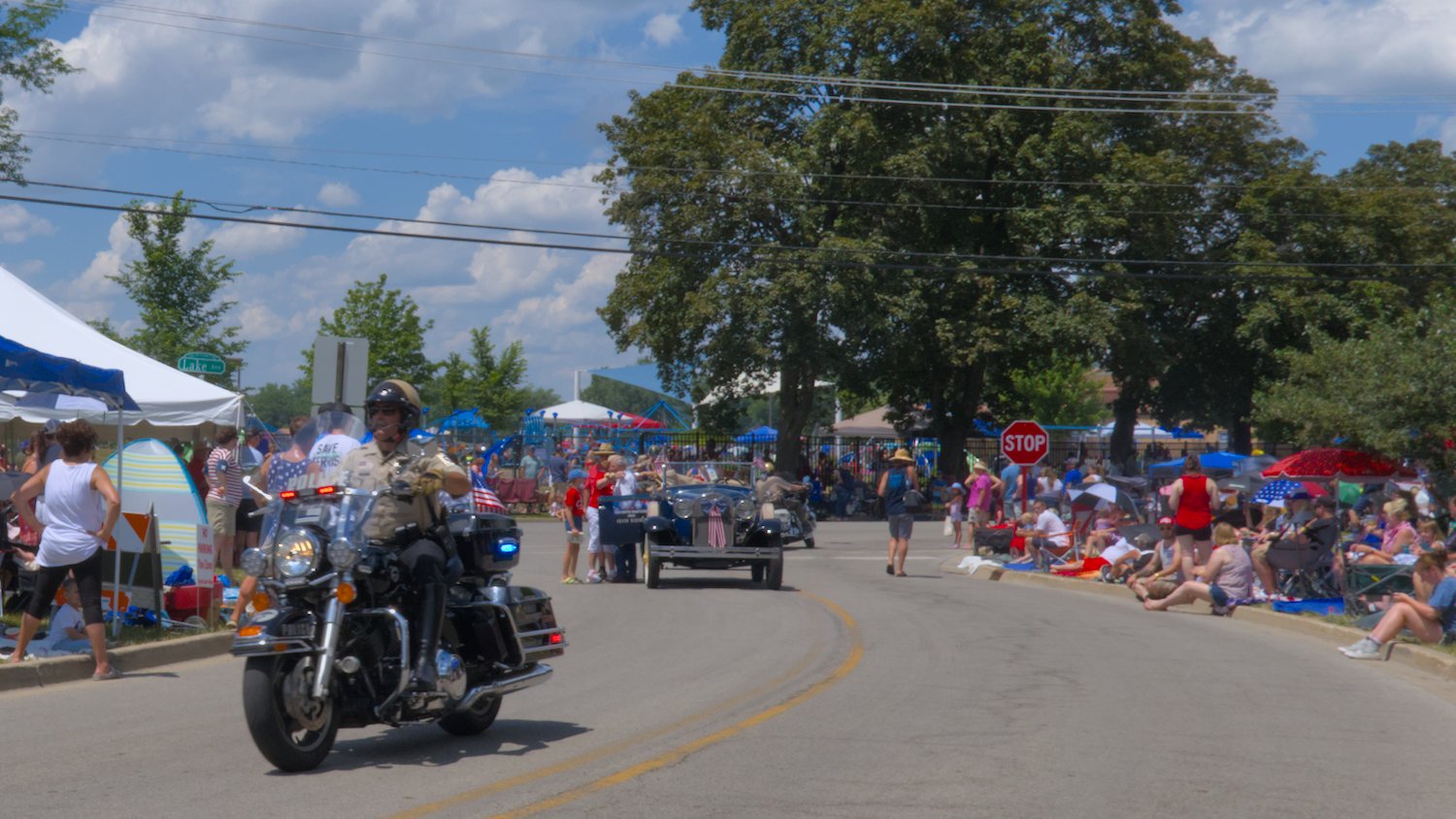 Police motorcycle, with Jim Athans dropping off Grand Marshall Kathryn Martens in the background.
