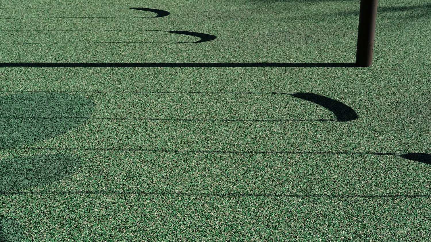 Shadows of swings against the playground surface.