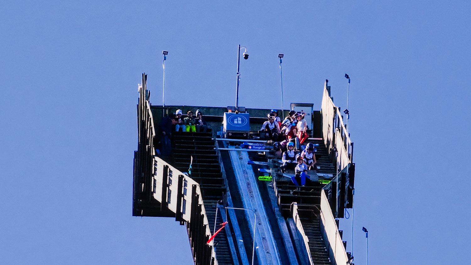 Ski jumpers seated at the top of the 70m tower at the 118th Annual Norge Ski Club Winter Tournament.