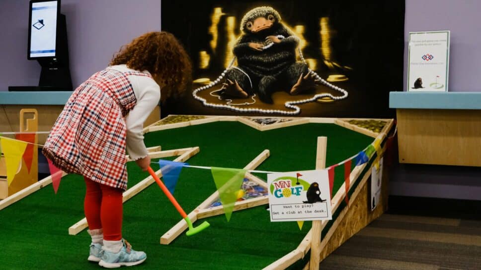 Young girl playing a mini-golf game in the library.