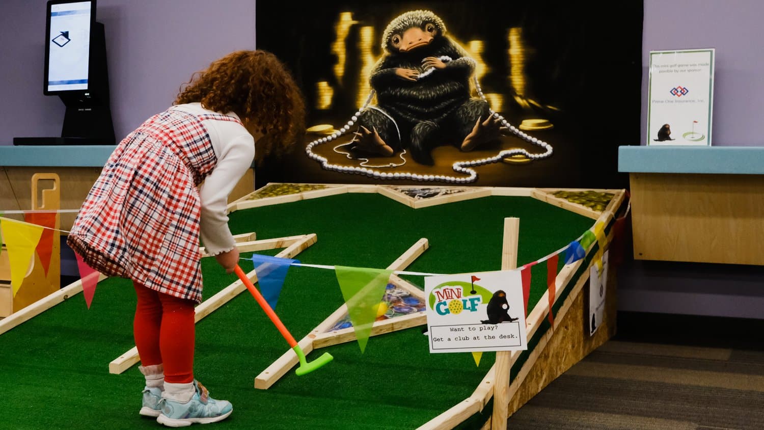 Young girl playing a mini-golf game in the library.