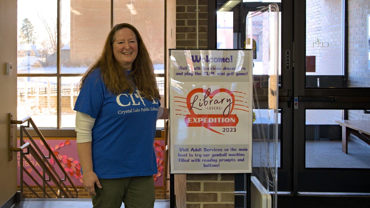 Seanine Brady standing next to the Library Lovers Expedition poster.