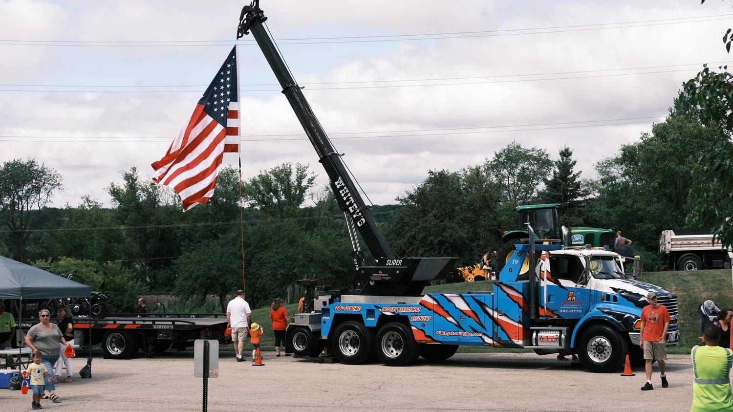 Heavy duty tow truck flying a large American flag.