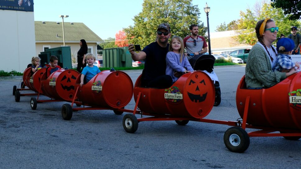 Kids and parents riding in the pumpkin barrels.