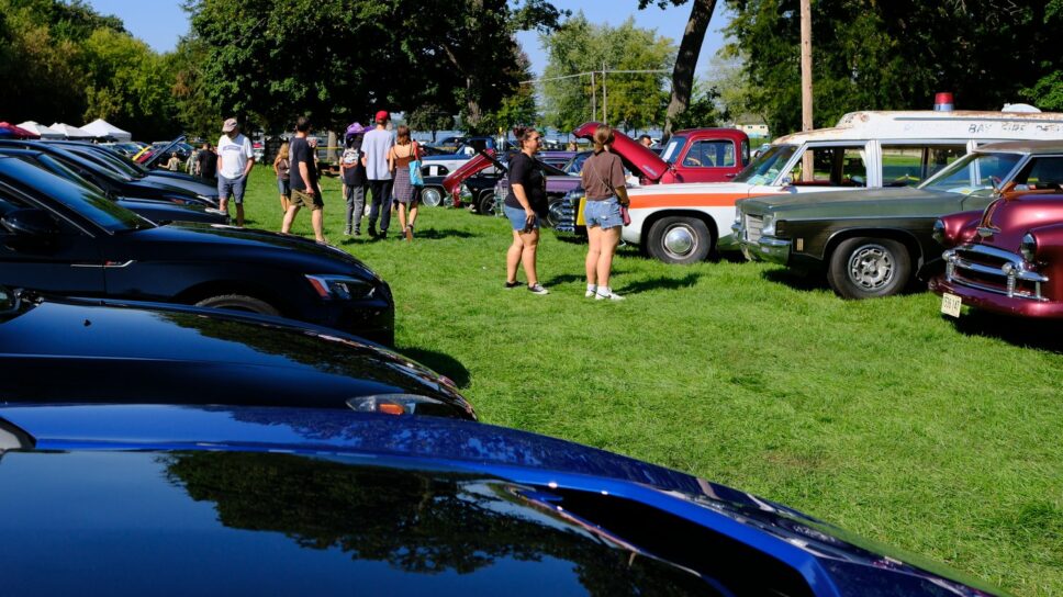 Spectators taking in the cars at the car show.