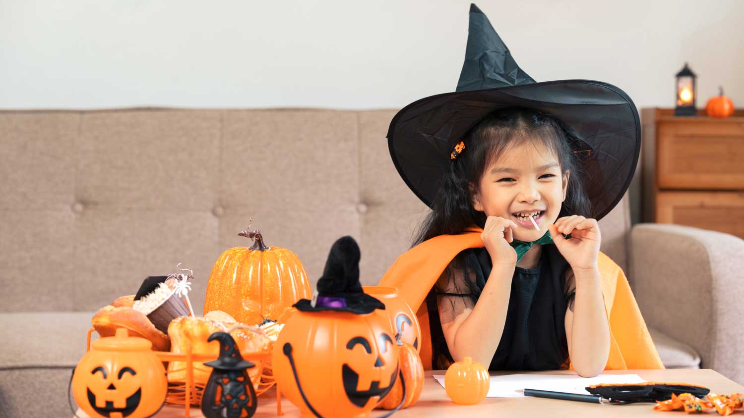 Girl in witch costume eating Halloween candy.