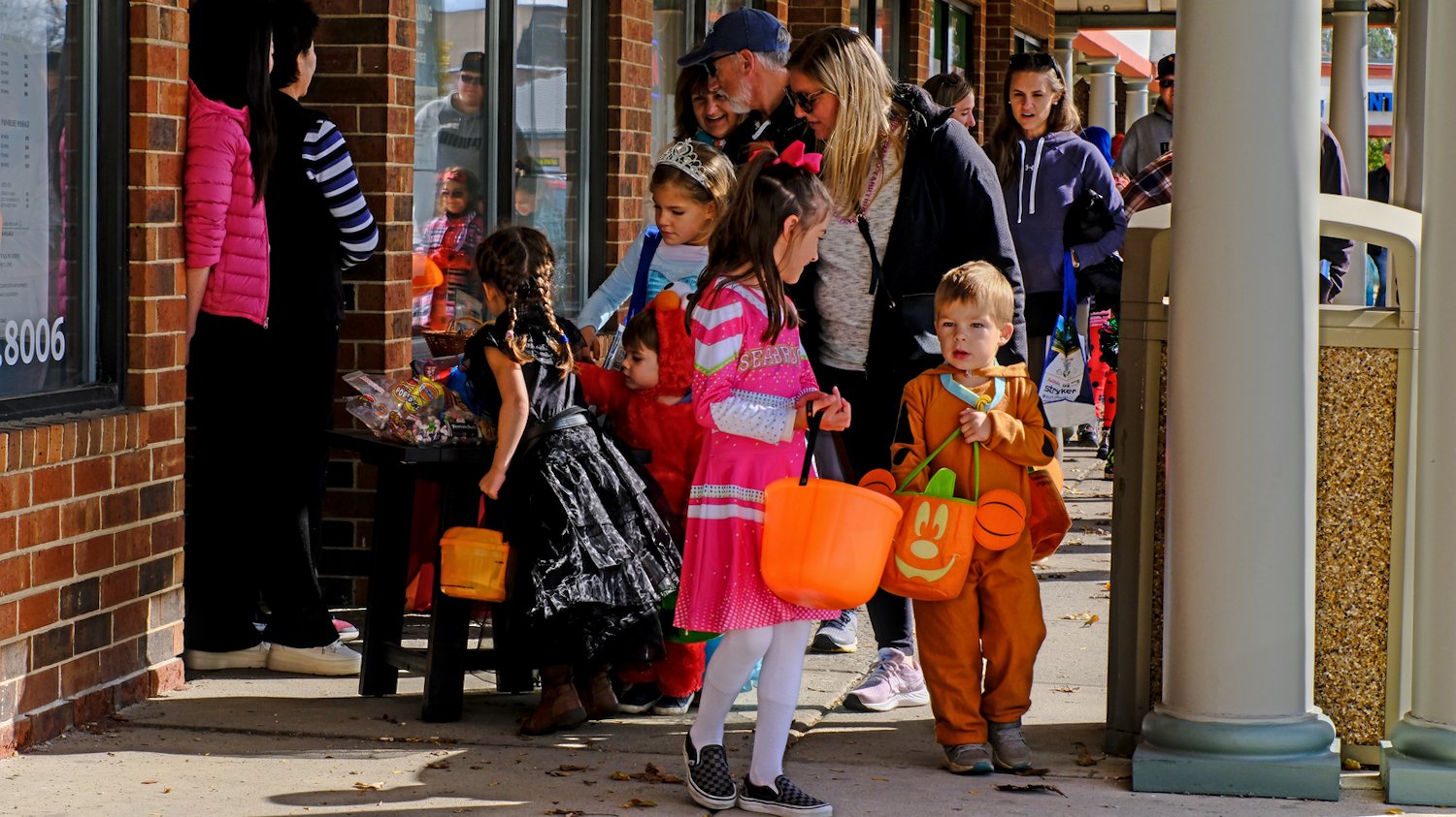 Trick-or-treaters filling their treat bags and buckets.