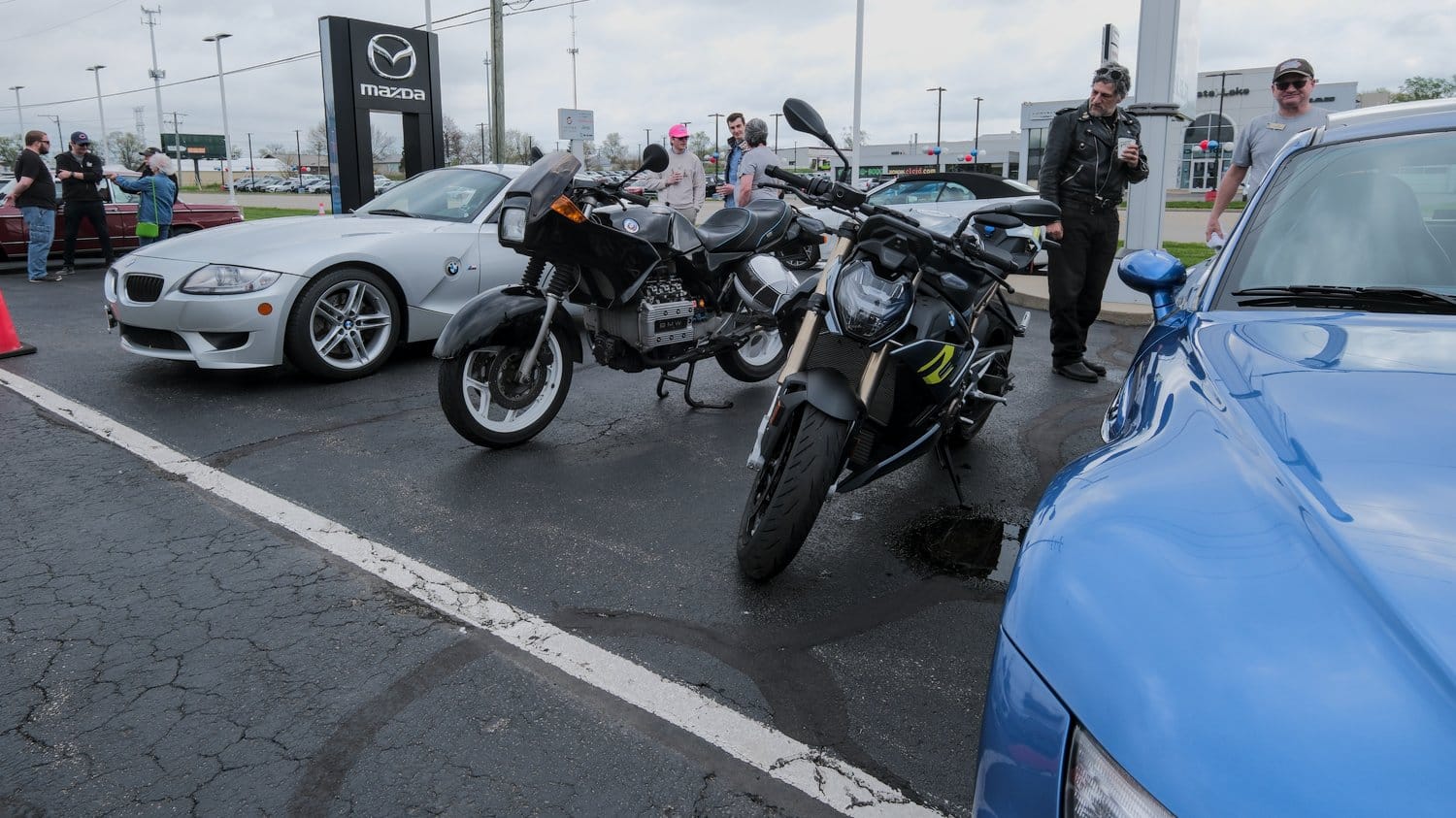 Two BMW motorcycles between BMW cars.