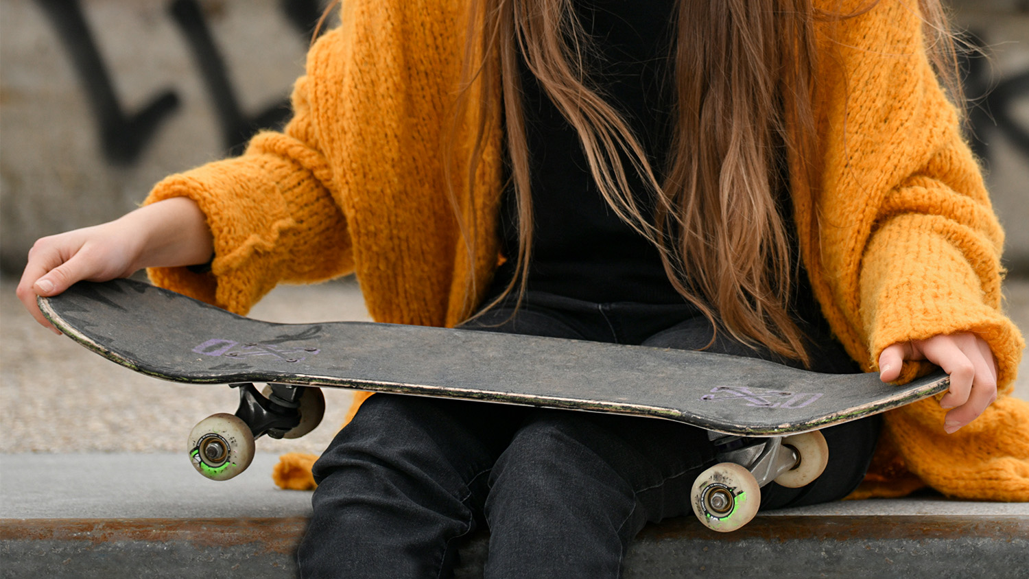Girl holding a skateboard.
